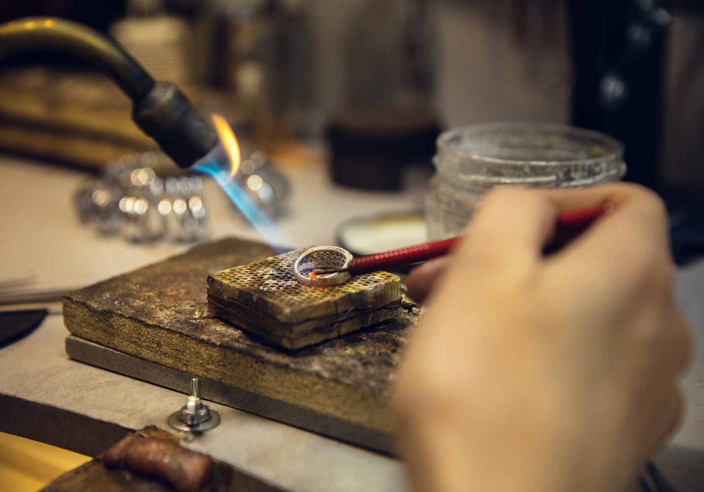 Close up hands of jeweller, goldsmiths making of golden ring with gemstone using professional tools. Craft production, precious and luxury jewel, hand made occupation. Workshop, artwork.